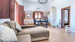 A living room with a sofa, dining table, and chairs, a kitchen in the background, and a chandelier. - Beautiful home in Adamuz (Adamuz)