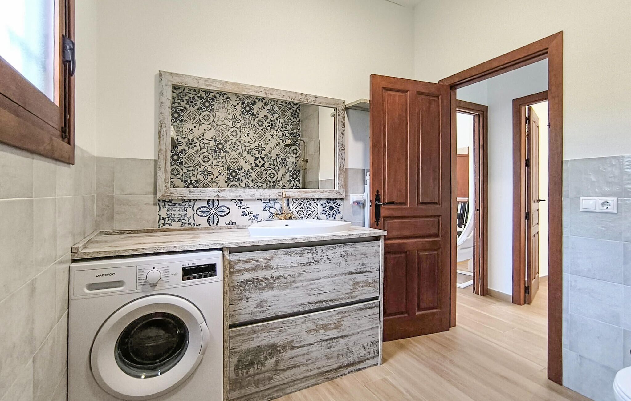 Un baño pequeño con lavadora, tocador de madera y salpicadero de azulejos.