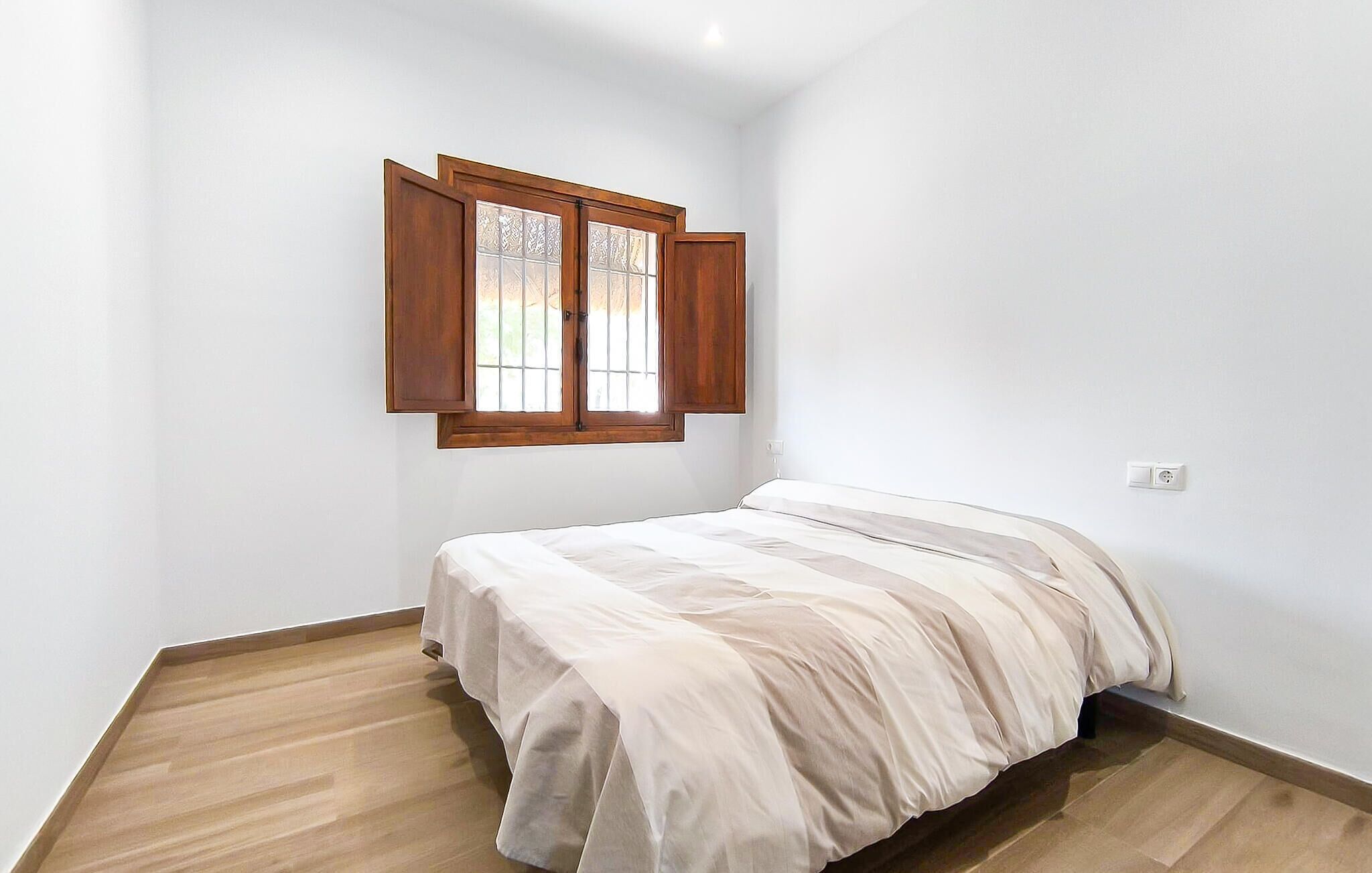 Ein kleiner, sauberer Raum mit einem Einzelbett, einem Holster mit Fensterlädchen und einer weißen Wand.