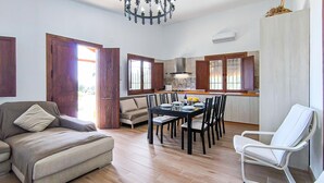 A spacious living room with a sofa, a dining table set for four, and a white chair. - Beautiful home in Adamuz (Adamuz)