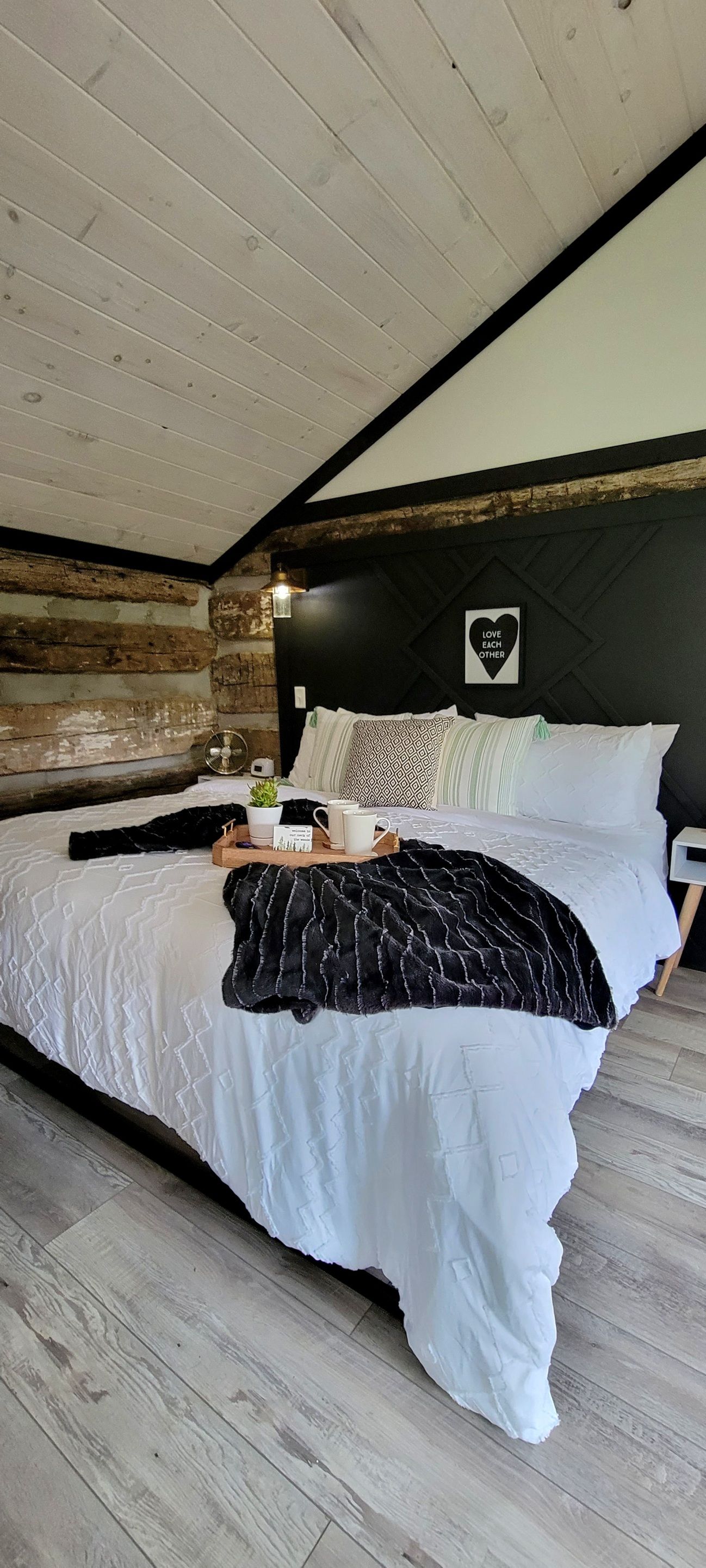 A bedroom with a large bed, a wall-mounted light, and a decorative sign.