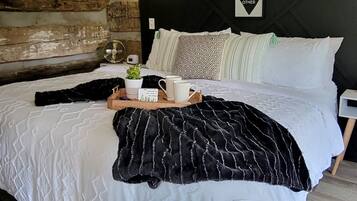 A bedroom with a large bed, a wall-mounted light, and a decorative sign.