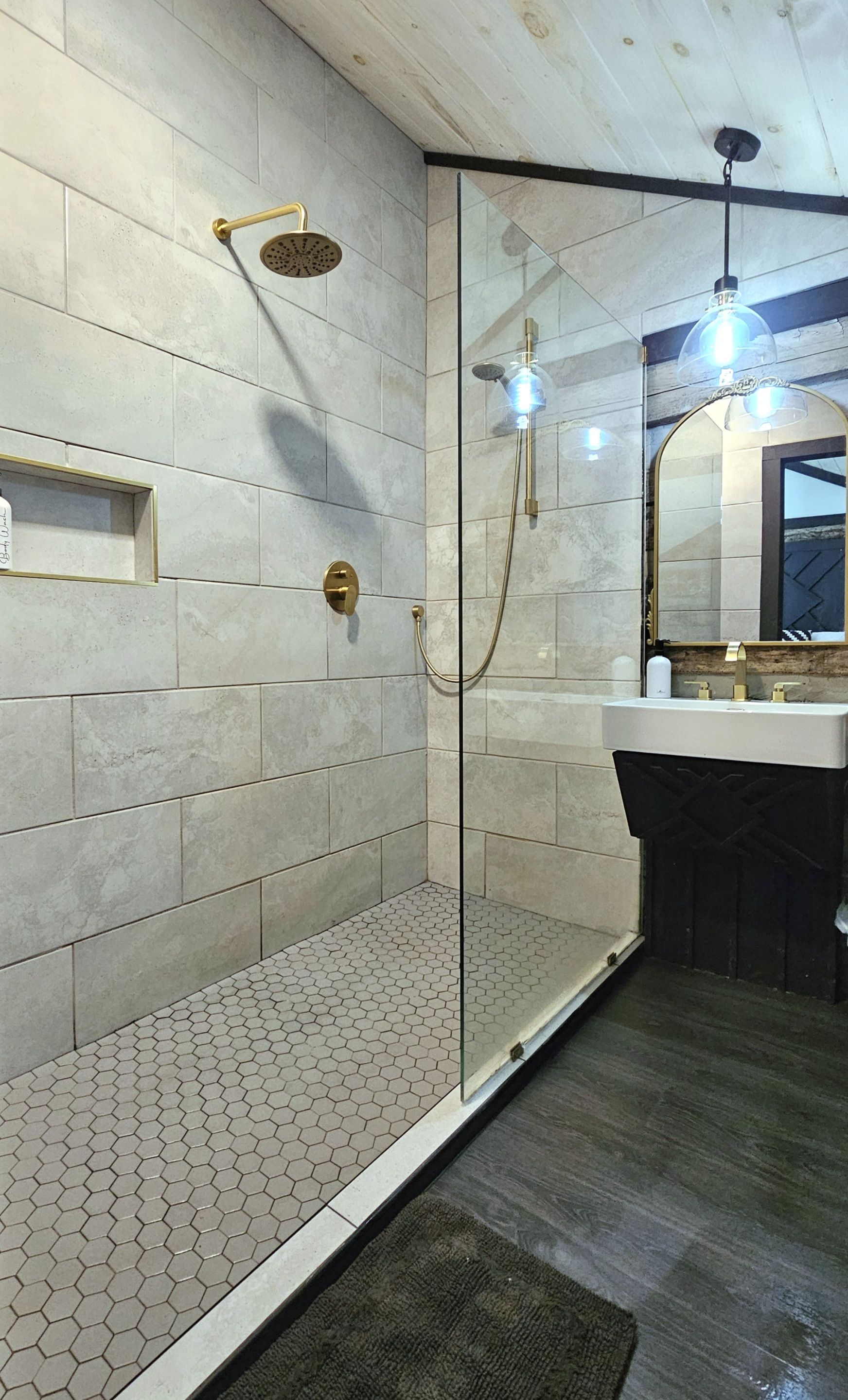 A modern bathroom with a glass-enclosed shower, a vanity with a mirror, and a hexagonal tile floor.