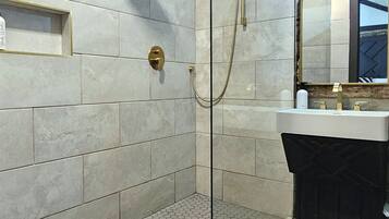 A modern bathroom with a glass-enclosed shower, a vanity with a mirror, and a hexagonal tile floor.