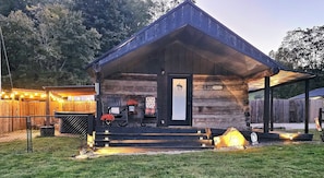 A rustic log cabin with a welcoming entrance, outdoor seating, and a well-lit porch area.