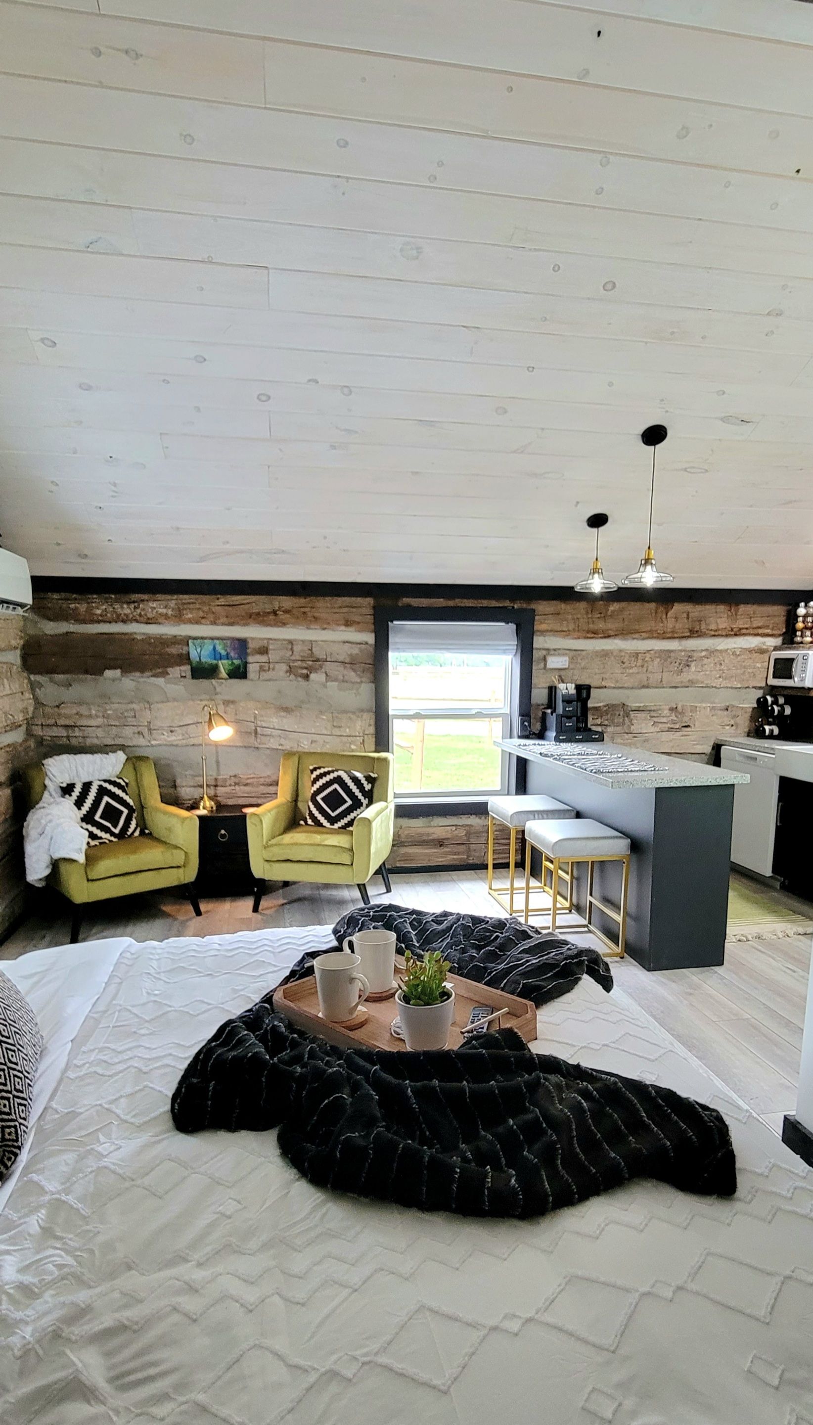 Une pièce confortable avec un lit, deux fauteuils, une table basse et un coin cuisine avec une fenêtre.