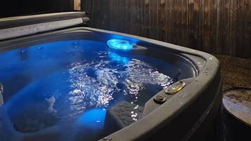 A hot tub with a wooden ceiling and a wooden fence in the background.
