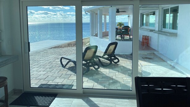 Een kamer met een schuifglasdeur die uitkomt op een terras met uitzicht op zee.