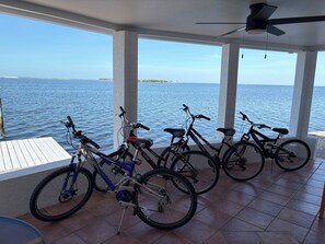 Un espacio cubierto con vista al mar, que incluye varias bicicletas y una mesa.