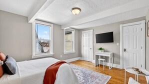 A bedroom with a bed, a desk, a chair, a TV, and a window. - Walk to Brady St, 2-story upper flat, Sleeps 7! (Milwaukee)