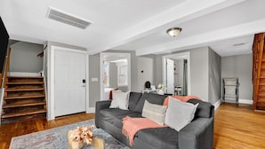 A living room with a grey sofa, wooden staircase, and a patterned rug. - Walk to Brady St, 2-story upper flat, Sleeps 7! (Milwaukee)