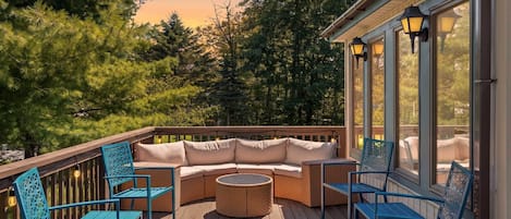 Una terraza de madera con un sofá curvo, dos sillones y una mesa redonda.