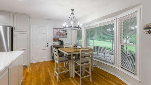 Una cocina con armarios blancos, una mesa de comedor de madera y una araña.