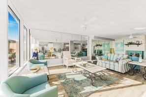 Ein geräumiges Wohnzimmer mit großem Fenster, Deckenventilator und einer Couch mit gestreiften Kissen.