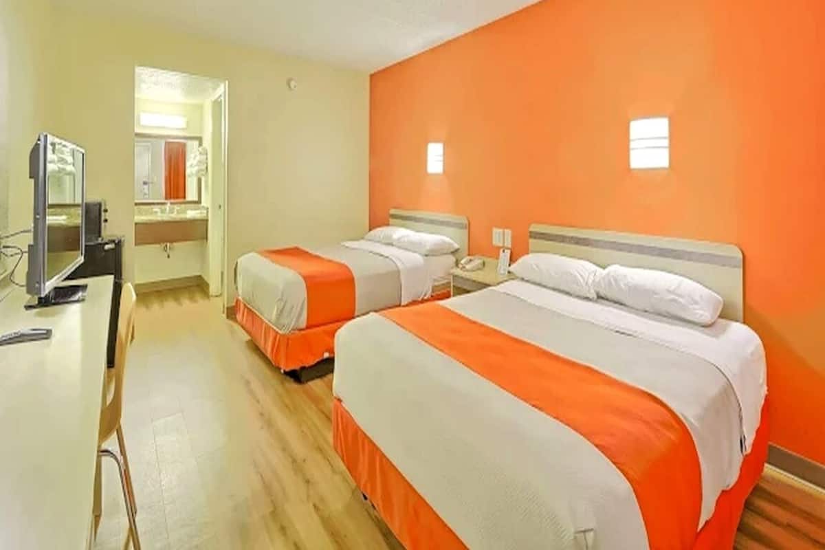 Una habitación de hotel con dos camas, un escritorio y una televisión.