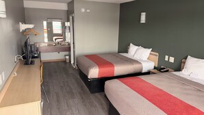 Ein Hotelzimmer mit zwei Betten, einem Schreibtisch mit Computer, einem Spiegel und einem durch eine geöffnete Tür einsehbaren Badezimmer.
