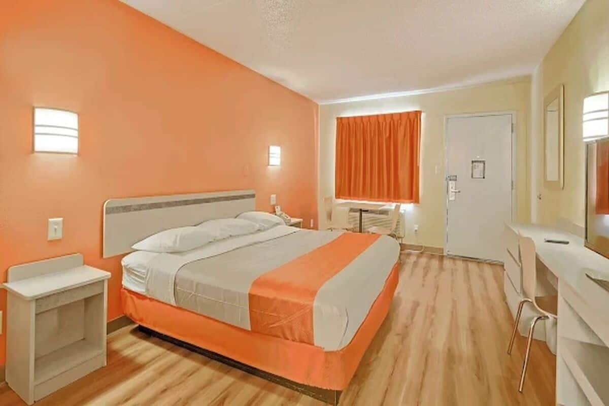 Una habitación de hotel con cama, escritorio, silla y puerta.