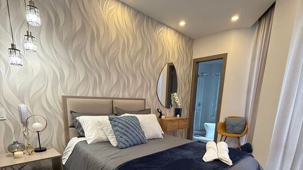 A modern bedroom with a large bed, bedside tables, a mirror, and a view of the bathroom. - Luxury suite in quito (Quito)