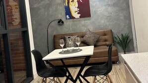 A modern living space with a dining table, brown sofa, and a painting on the wall. - Luxury suite in quito (Quito)