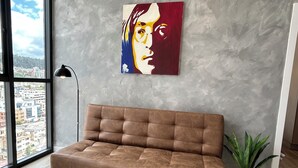 A modern living room with a brown sofa, a painting on the wall, a floor lamp, and a potted plant. - Luxury suite in quito (Quito)
