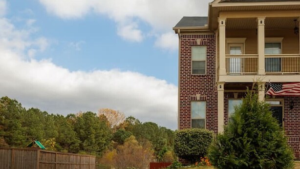A two-story building with a brick facade and a balcony on the upper floor.