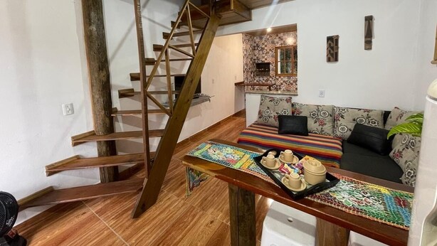 A wooden staircase leading to a loft bedroom with a bed and a small table with cups and a tray. - Cabin surrounded by nature, close to the beach and dunes. (Imbituba)