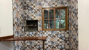 A small room with a tiled wall, a window, and a wooden shelf. - Cabin surrounded by nature, close to the beach and dunes. (Imbituba)