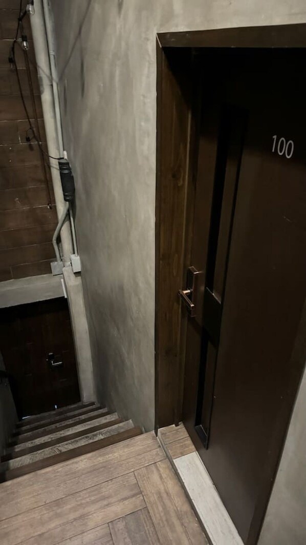 A staircase leading to a dark wooden door with the number 100.