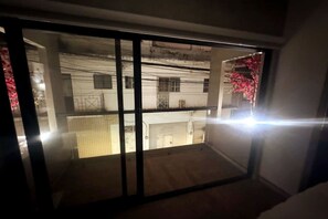 A room with a view of a building with multiple windows and a balcony.