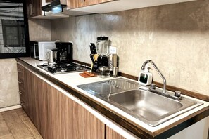 Eine moderne Küche mit Gasherd, Kaffeemaschine und Spüle aus Edelstahl.