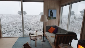Ein gemütliches Zimmer mit einer Couch, einem Sessel, einem Tisch mit Büchern, einer Lampe und einem Kamin.