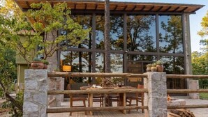 A wooden deck with stone pillars, a dining table, and chairs. - Cabin La Promesa | Canyon Views (Durango)