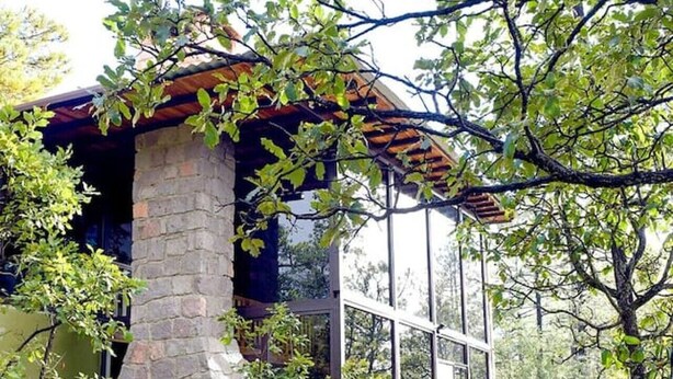 A stone building with a glass door and a small porch. - Cabin La Promesa | Canyon Views (Durango)