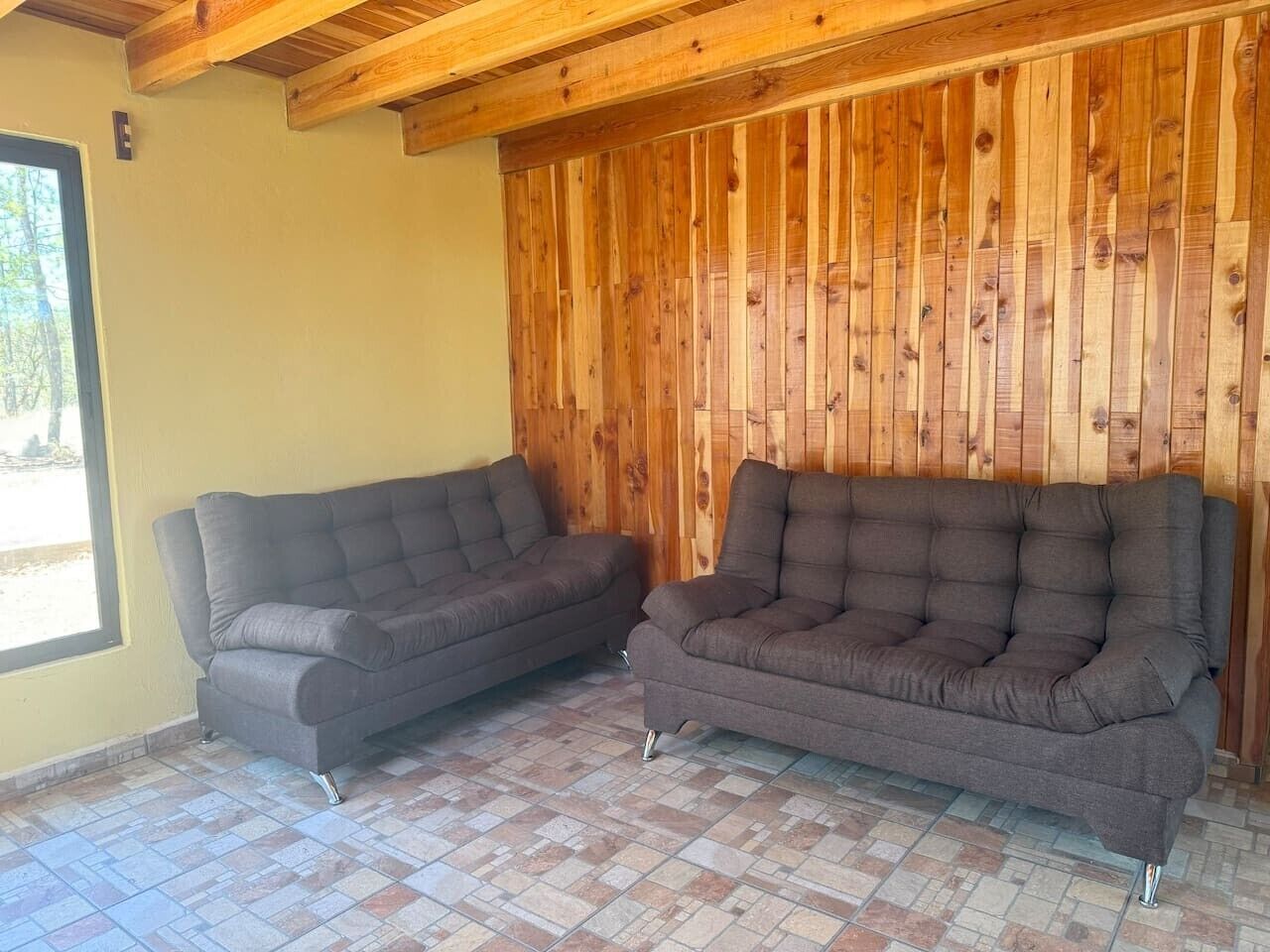 Ein Zimmer mit zwei Sofas, einer Holzwand und einem gefliesten Boden.