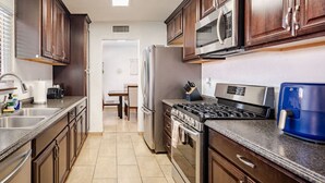 A kitchen with dark wooden cabinets, stainless steel appliances, and a tiled floor. - The Pool House New 2-Story Home Near Strip (Las Vegas)