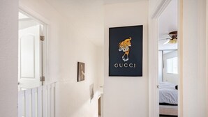 A hallway with a white door, a framed picture, and a black Gucci logo on the wall. - The Pool House New 2-Story Home Near Strip (Las Vegas)