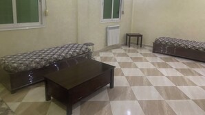 A living room with a checkered floor, a sofa, a coffee table, and a radiator. - Apartment Aloue for a better stay with us welcome (Café chergui)