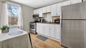 A modern kitchen with white cabinets, stainless steel appliances, and a wooden floor. - Brady St Base, 2BR Flat, Comfortably Sleeps 5 (Milwaukee)
