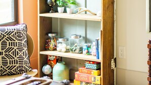 A room with a wooden bookshelf containing various items, a globe, and a wicker wreath on the door.