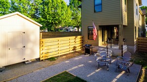 A house with a garage, a barbecue grill, and outdoor seating.