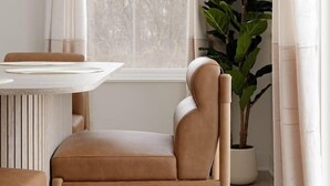 Quarto com janela, cadeira, mesa e planta em vaso.