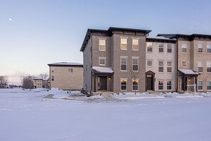 A multi-story building with a symmetrical facade, large windows, and a central entrance. - Brand New Home | Quiet Community Near Indianapolis (Noblesville)