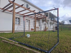 A soccer goal in a grassy area with a house in the background.