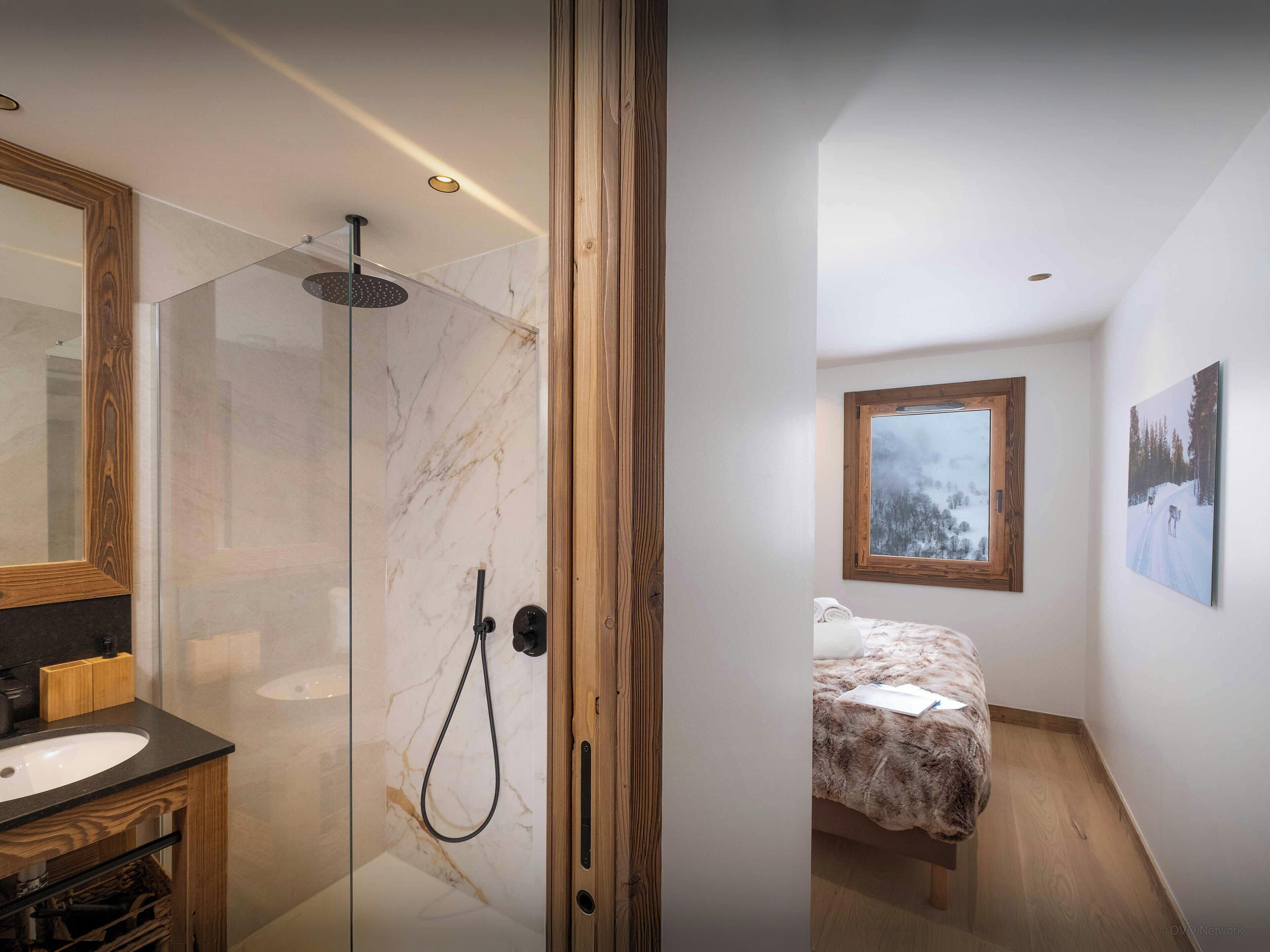 Ein modernes Badezimmer mit einer ein Glasfachwerk-Duschkabine, einem Holzkosmetikschrank und einer Marmor-Spritzschutzwand.