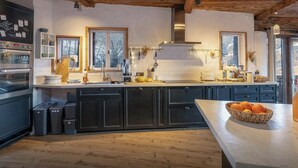 A modern kitchen with wooden beams, built-in appliances, and a large window.