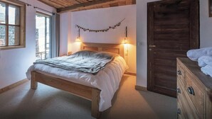 Une chambre à coucher avec un lit en bois, deux lampes de chevet, une porte en bois et une fenêtre avec des rideaux.