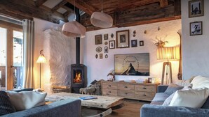 A cozy living room with a fireplace, wicker furniture, and a collection of framed pictures on the wall.