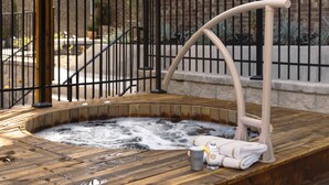 Ein Whirlpool mit Holzboden, Metallgeländer und Handtuchhalter.