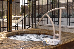 Ein Whirlpool mit Holzboden, Metallgeländer und Handtuchhalter.