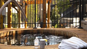 Eine Holzterrasse mit Whirlpool, einer Wasserflasche, einem Glas und einem Handtuch.